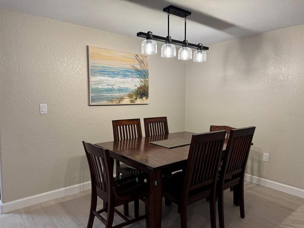 A dining room features a dark wood table with six chairs under a modern light fixture — 6154 MIDNIGHT PASS ROAD UNIT C15, SARASOTA, FL