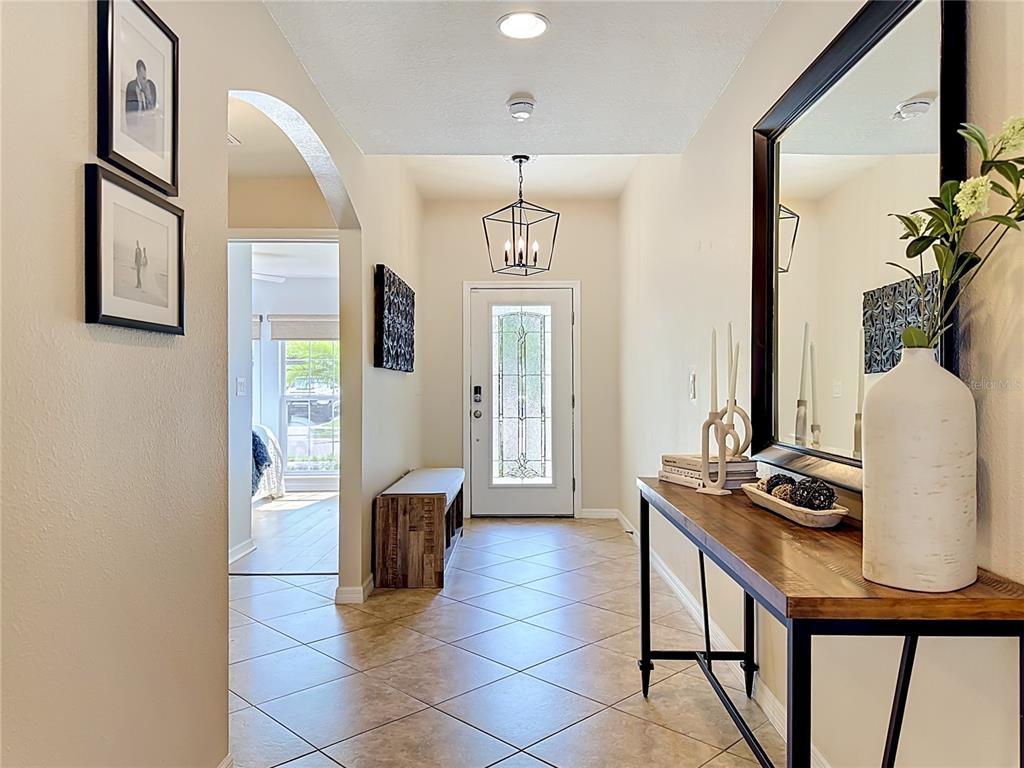A tiled entryway features a console table, a bench, and a front door with glass — 12033 GRAND KEMPSTON DRIVE, GIBSONTON, FL