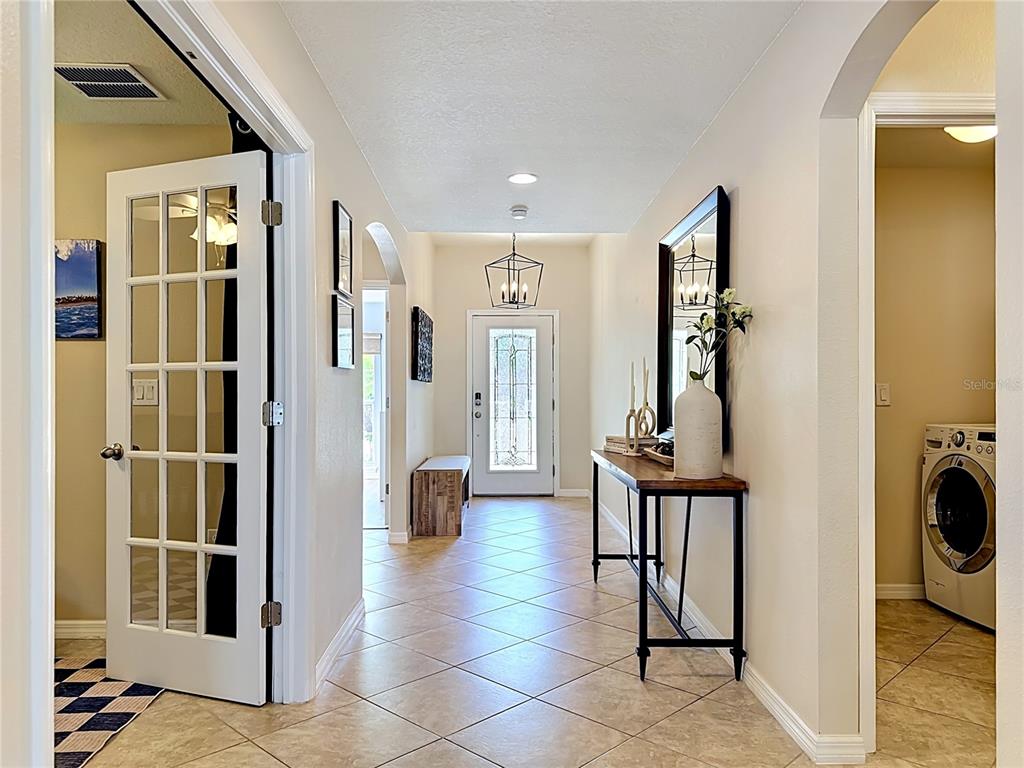 A tiled entryway features a front door, a console table, and a laundry room entrance — 12033 GRAND KEMPSTON DRIVE, GIBSONTON, FL