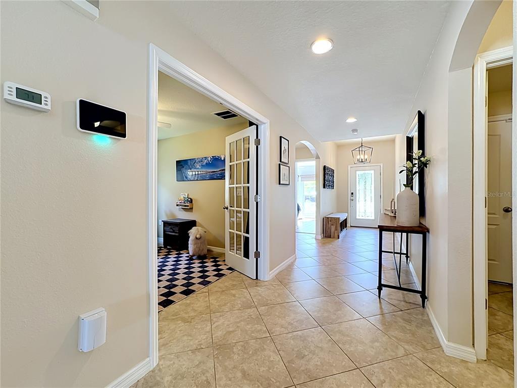 A tiled hallway leads to a front door, with a French-door room on the left — 12033 GRAND KEMPSTON DRIVE, GIBSONTON, FL