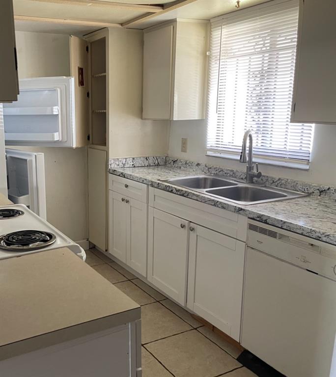 A kitchen features white cabinets, granite countertops, a double sink, and a white dishwasher — 4013 CEDARLIMB COURT, TAMPA, FL