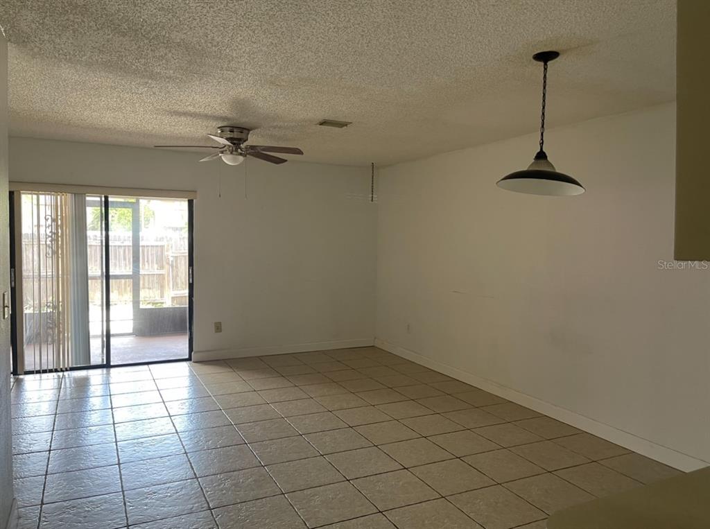 An open living area features beige tile flooring, a ceiling fan, and a sliding glass door — 4013 CEDARLIMB COURT, TAMPA, FL