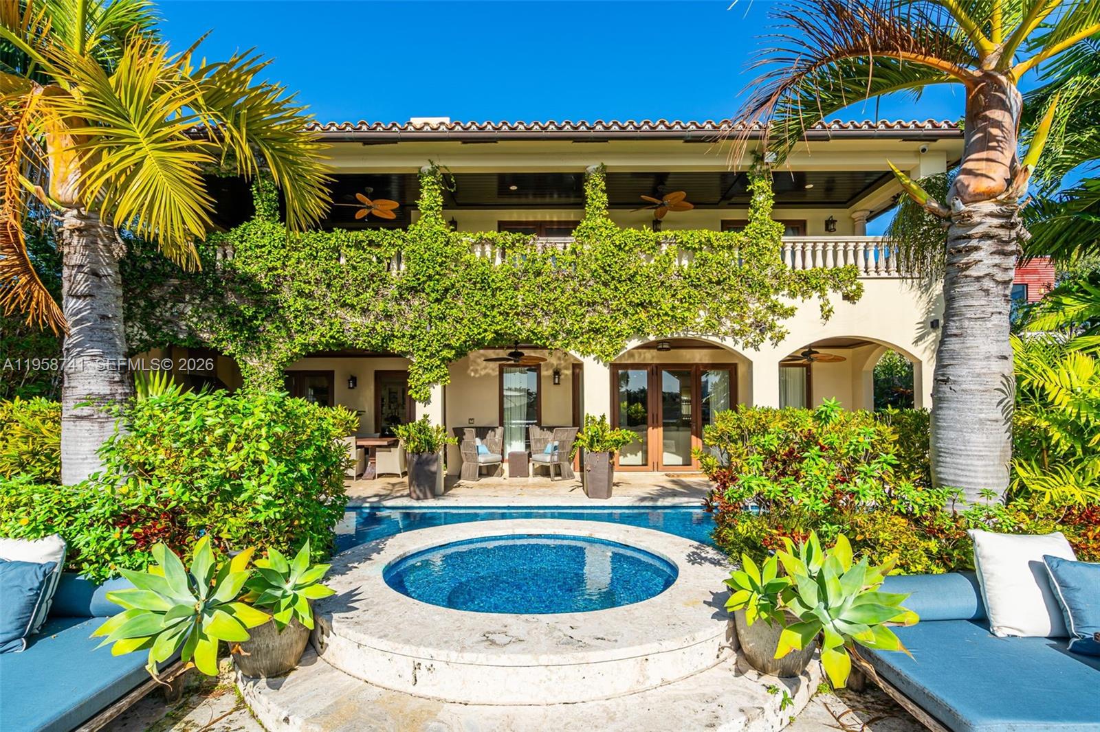 A two-story house with a vine-covered balcony overlooks a circular pool and patio area — 1398 Bay Dr, Miami Beach FL 33141, MIAMI BEACH, FL