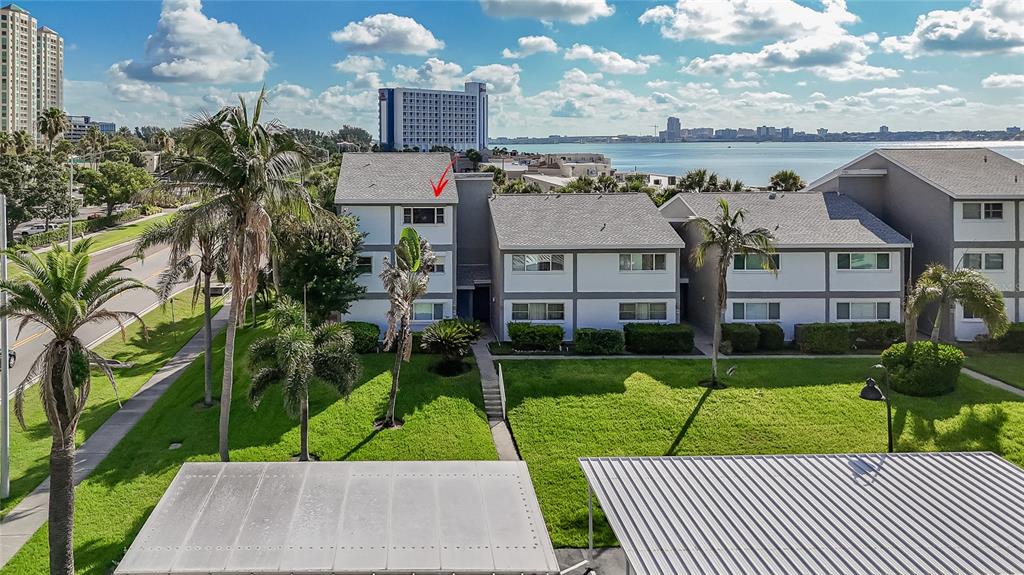 An exterior view of a multi-story apartment complex with a red arrow pointing toward a window — 1301 GULF BOULEVARD UNIT 201, CLEARWATER BEACH, FL