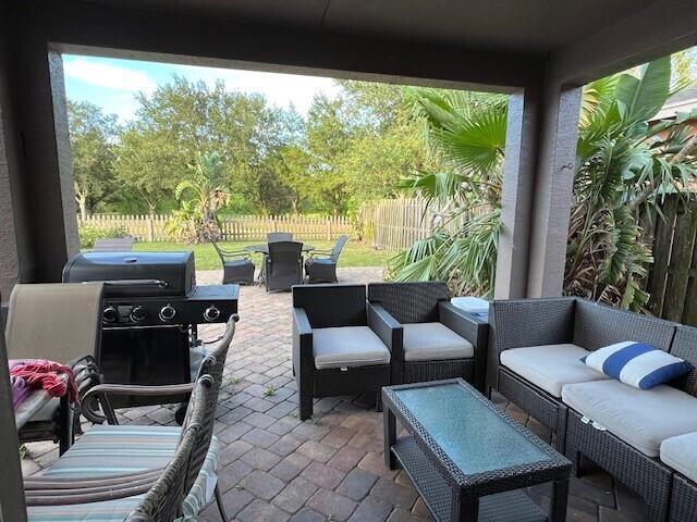 A covered patio features a brick floor, outdoor furniture, a grill, and a fenced backyard — 144 Blue Grotto Drive, Fort Pierce FL 34945, FORT PIERCE, FL