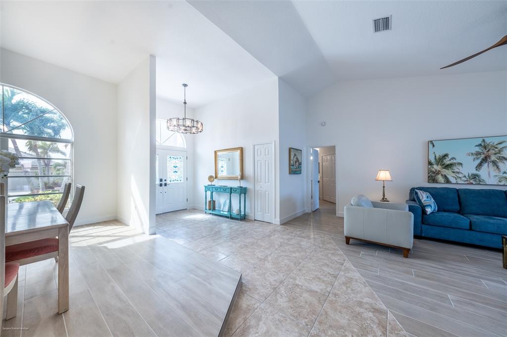 An open-concept living and dining area features tile flooring, vaulted ceilings, and a blue sofa — 2572 BRAZILIA COURT, PUNTA GORDA, FL