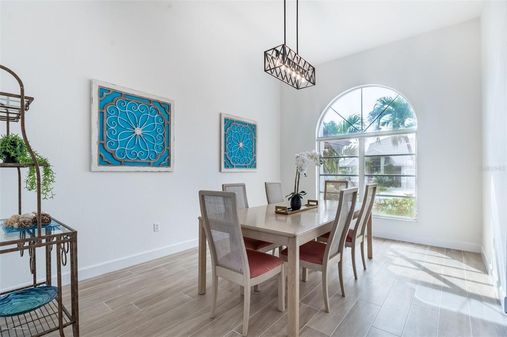 A dining room features a light wood table, six chairs, a metal chandelier, and arched windows — 2572 BRAZILIA COURT, PUNTA GORDA, FL