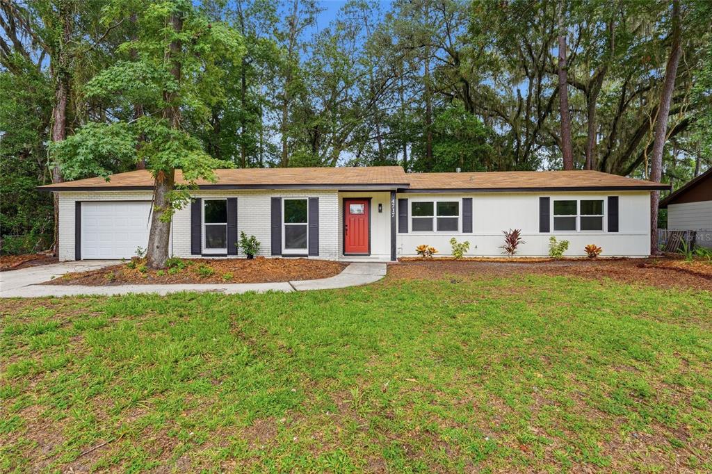 A single-story white brick house with a red front door and a one-car garage — 4717 NW 31ST TERRACE, GAINESVILLE, FL