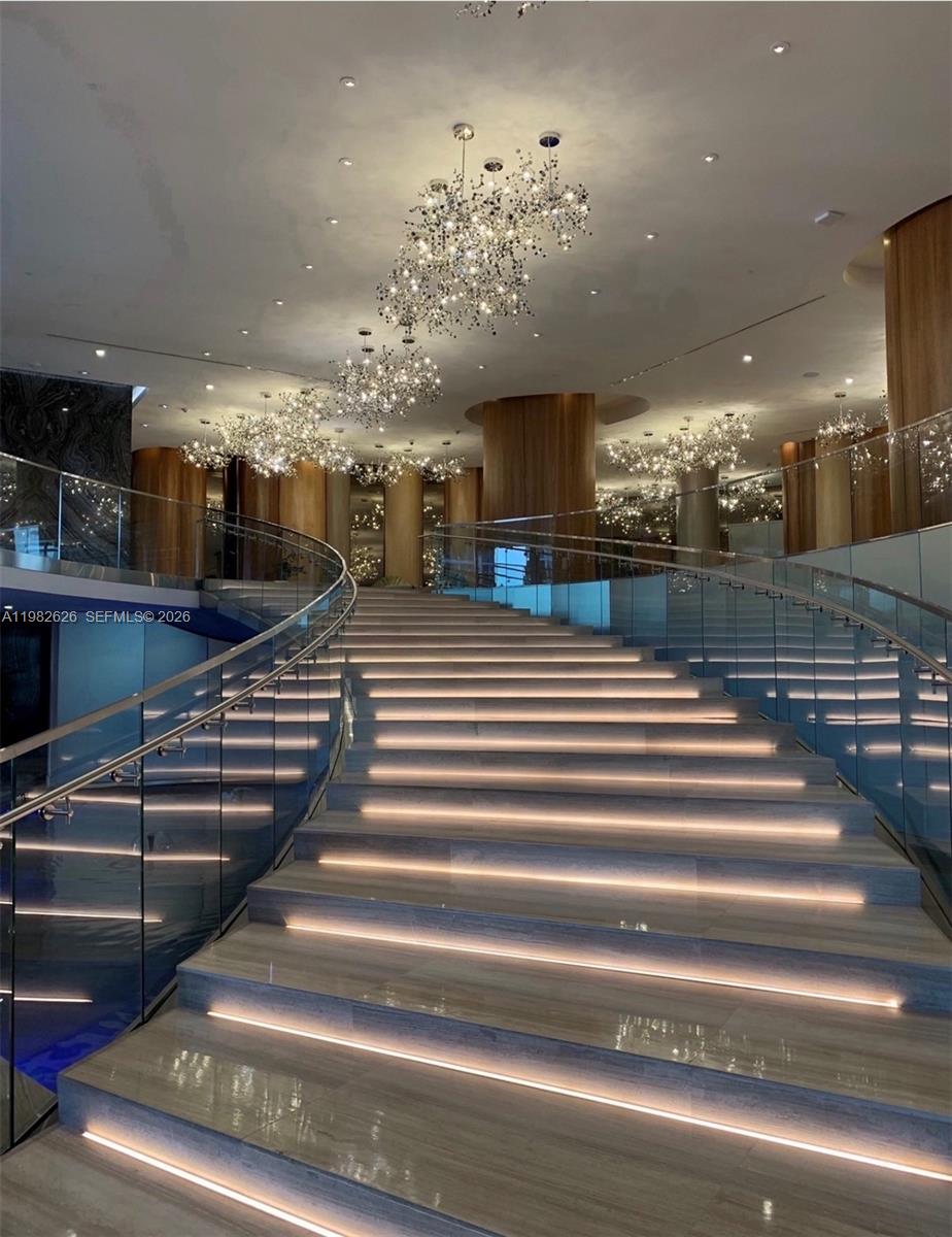 A grand staircase with illuminated steps and glass railings leads up to a lobby area — 488 NE 18TH # 2703, Miami FL 33132, MIAMI, FL