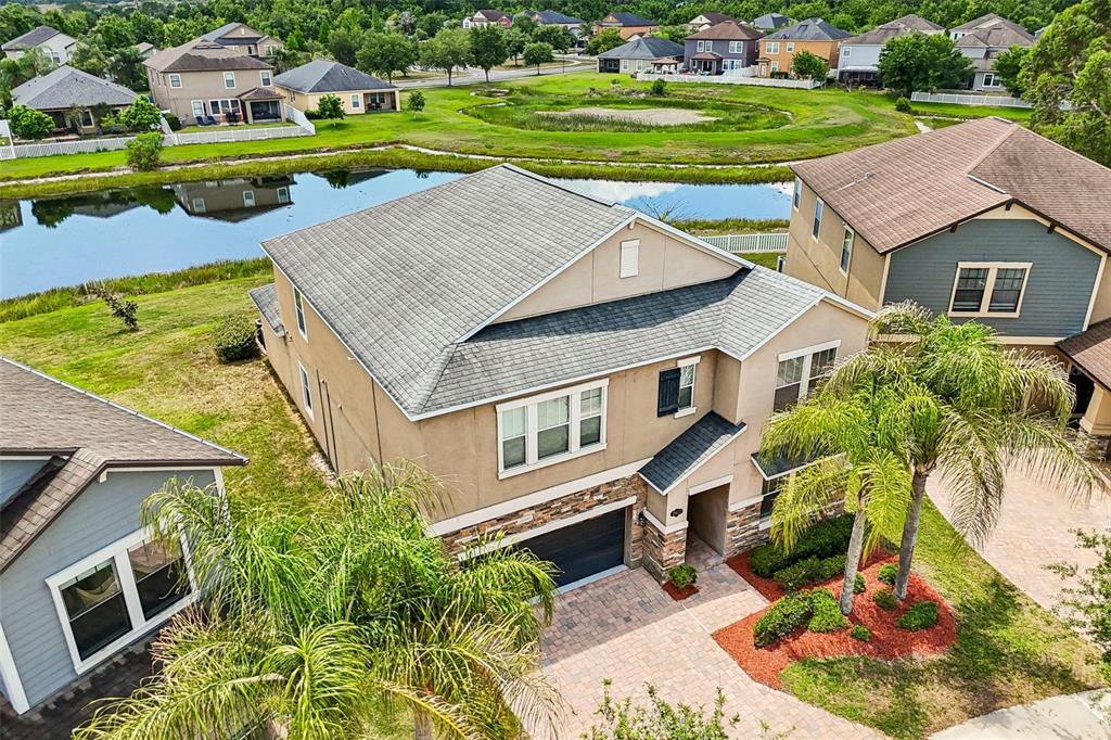 An aerial view shows a two-story suburban house with a paved driveway and a pond — 19417 PADDOCK VIEW DRIVE, TAMPA, FL