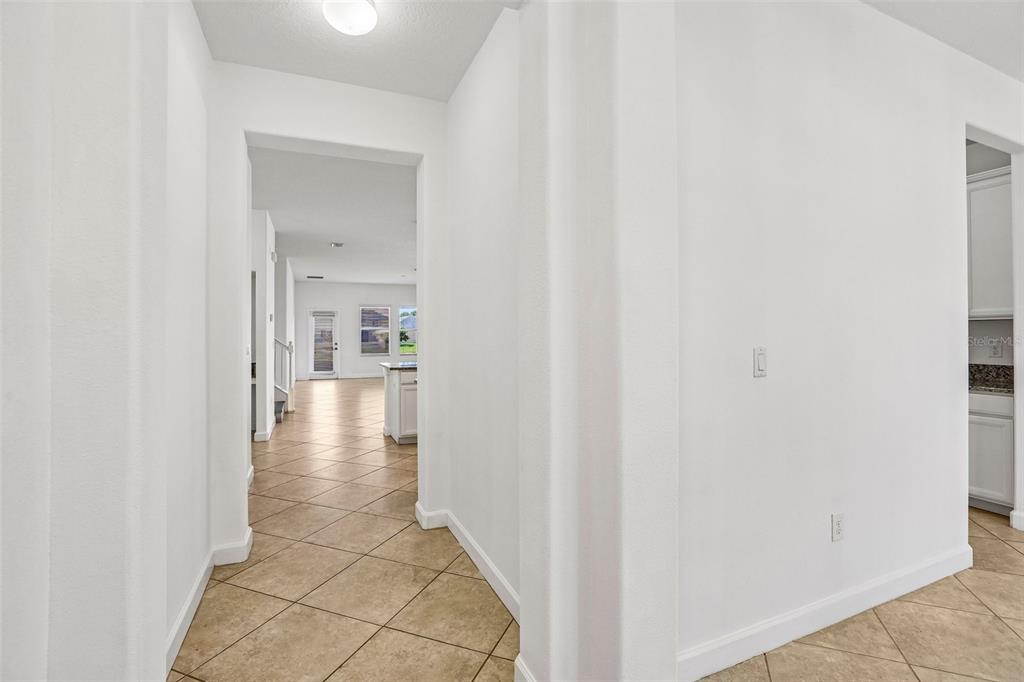 A view through a hallway with tile flooring leading to an open kitchen and living area — 19417 PADDOCK VIEW DRIVE, TAMPA, FL
