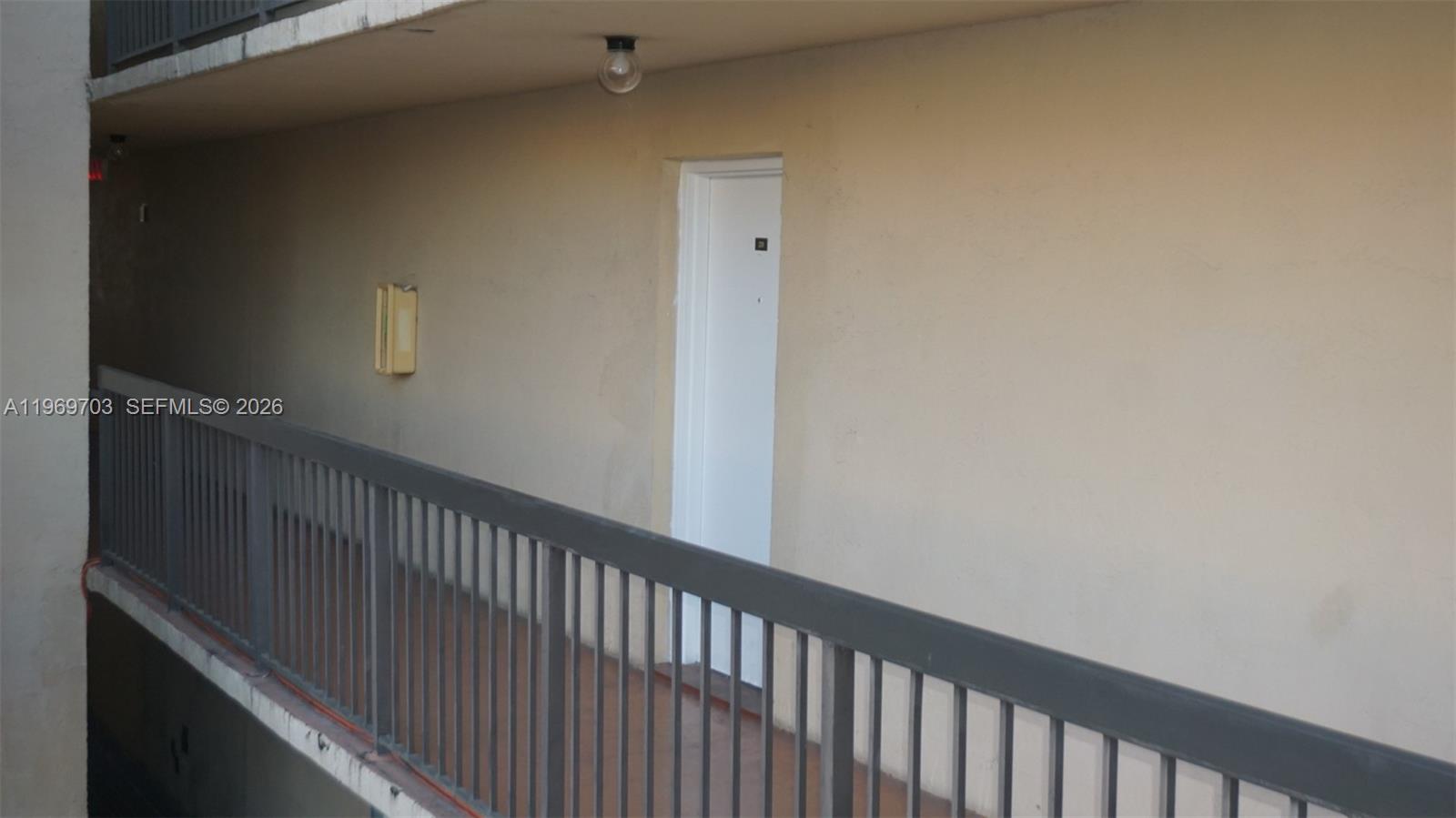 A white door is set into a beige wall along an outdoor apartment building walkway — 995 SW 84th Ave # 218, Miami FL 33144, MIAMI, FL