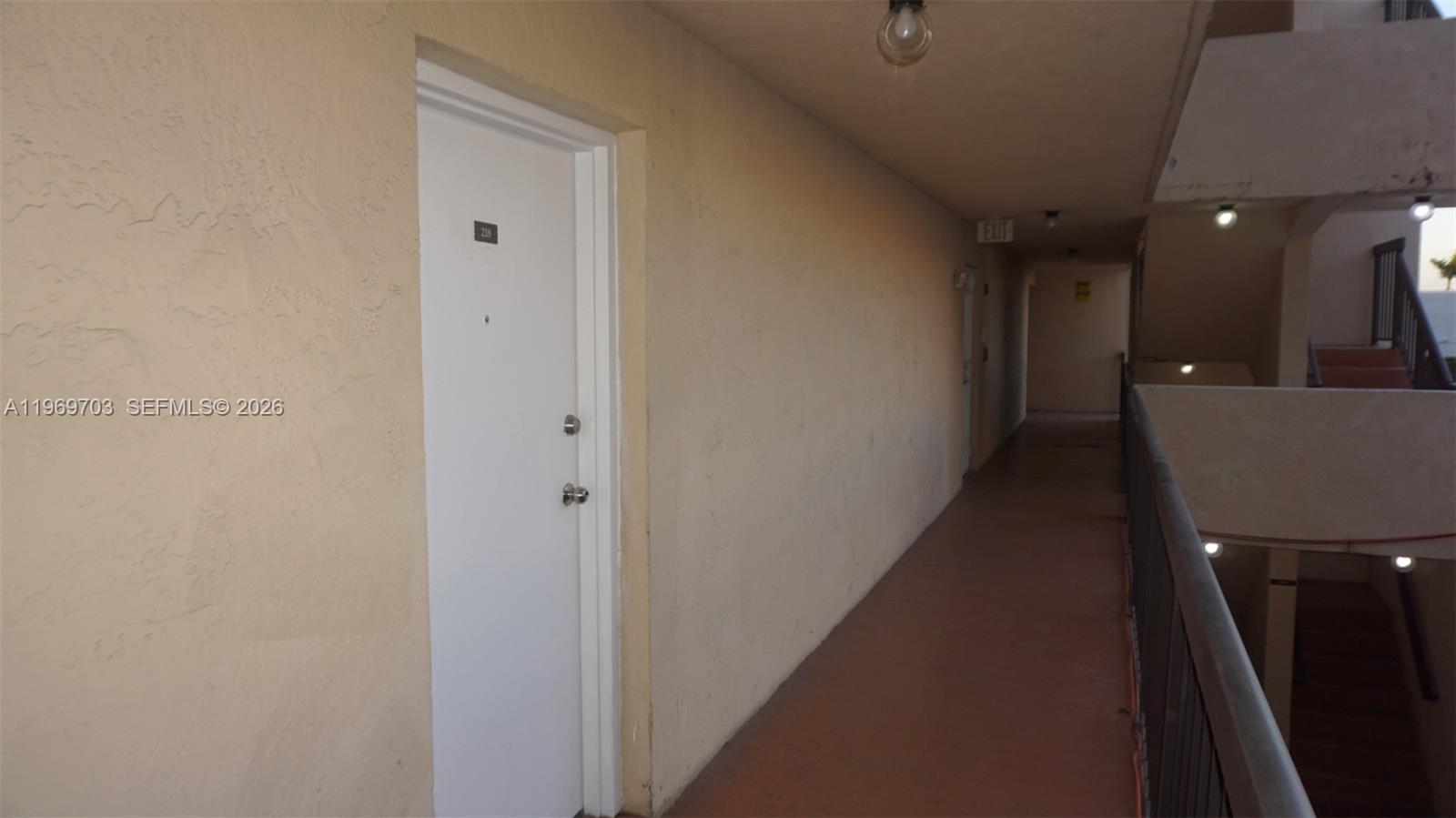 A white door with a number plate sits along an outdoor apartment building walkway — 995 SW 84th Ave # 218, Miami FL 33144, MIAMI, FL