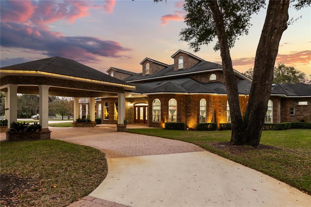 A large brick house with a porte-cochère and arched windows at sunset — 1501 LAKE MARKHAM ROAD, SANFORD, FL