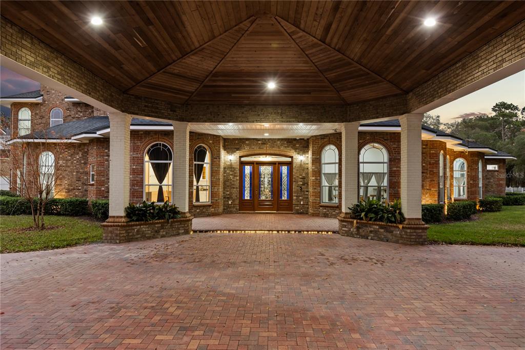 A brick house features a large covered entryway with a wooden ceiling and white columns — 1501 LAKE MARKHAM ROAD, SANFORD, FL