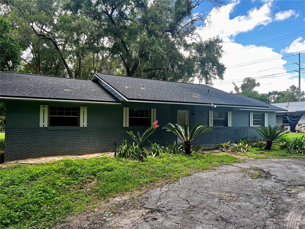 A single-story house with a gray brick exterior, dark roof, and light-colored window shutters — 2948 NE 14TH AVENUE, OCALA, FL