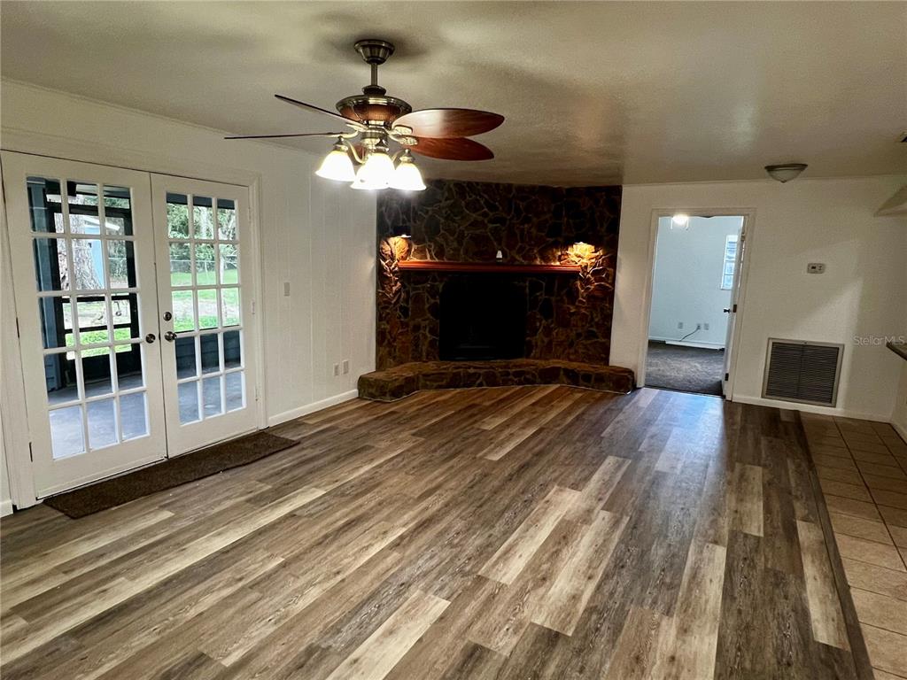 A living room features wood-look flooring, a stone corner fireplace, and French doors leading outside — 2948 NE 14TH AVENUE, OCALA, FL