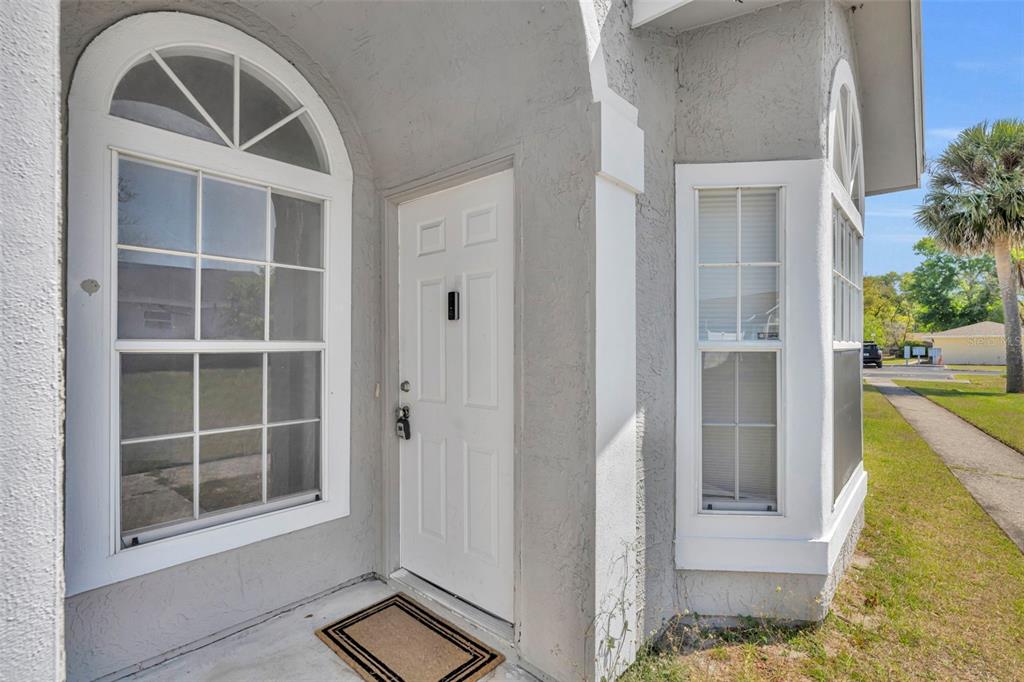 A white front door sits between two windows on the exterior of a gray house — 331 SAN GABRIEL STREET, WINTER SPRINGS, FL