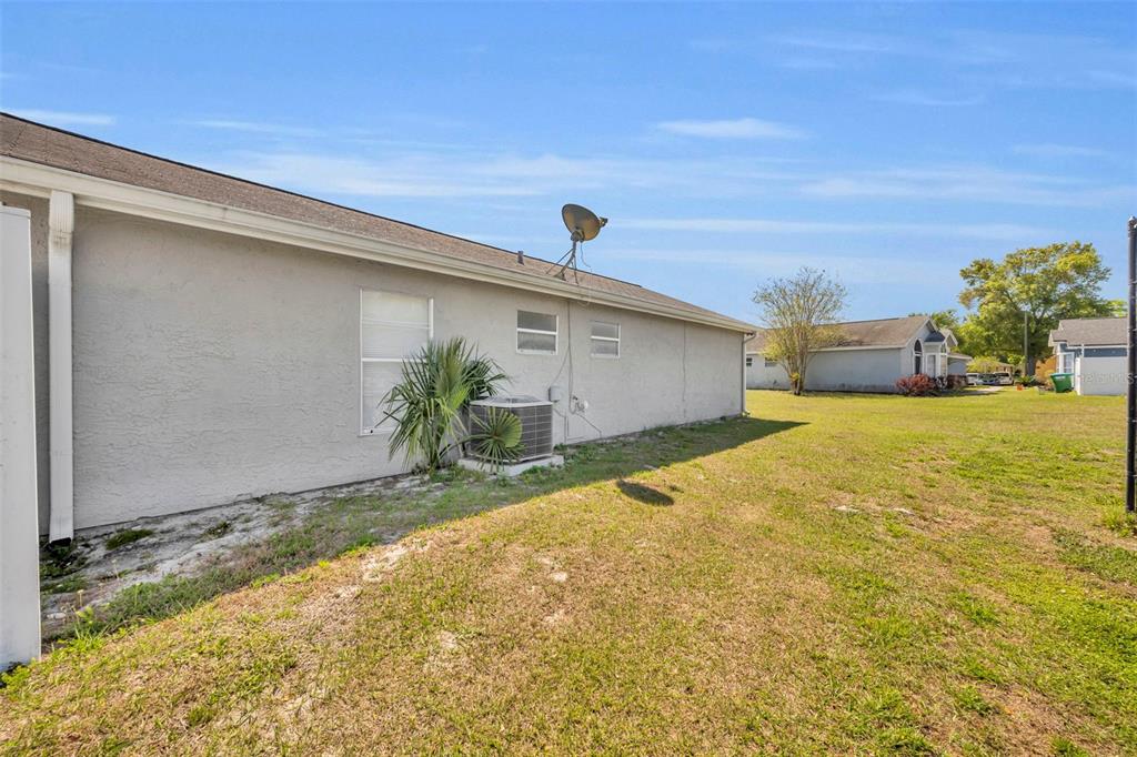 The exterior side view of a house features a stucco wall, an air conditioning unit, and a satellite dish — 331 SAN GABRIEL STREET, WINTER SPRINGS, FL