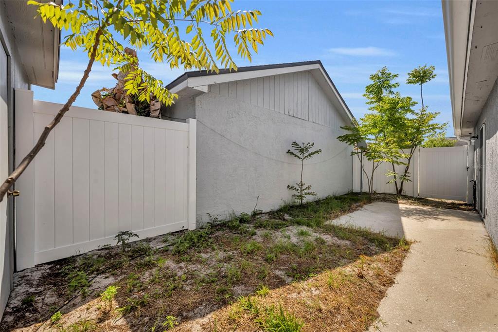 A side yard features a concrete walkway, a white vinyl fence, and a stucco wall — 331 SAN GABRIEL STREET, WINTER SPRINGS, FL
