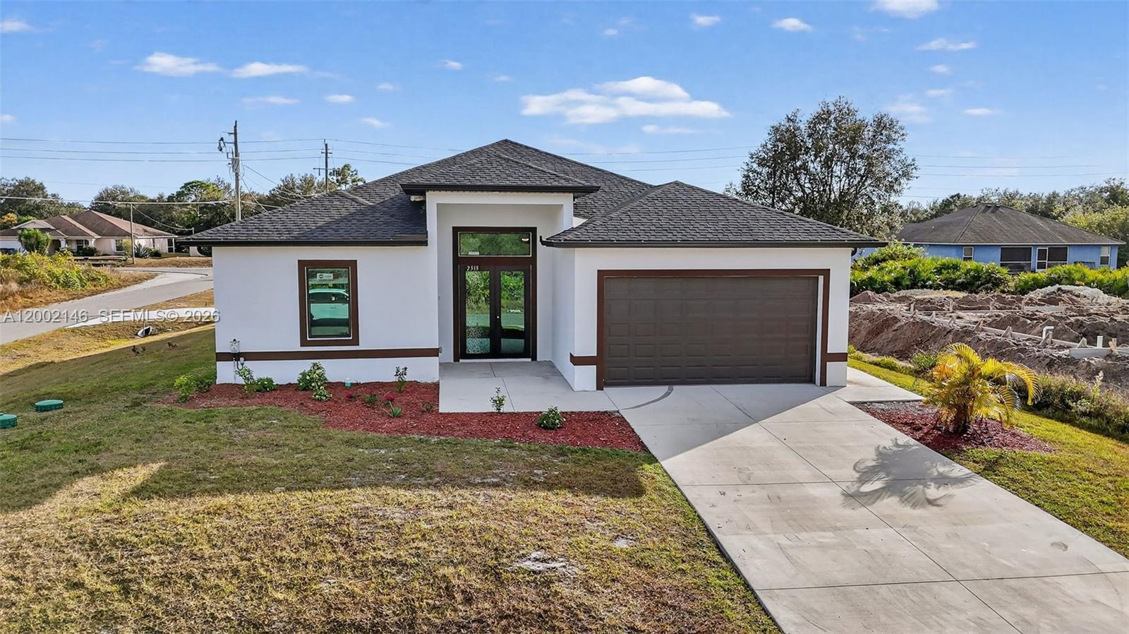 A modern, single-story house with a white exterior, dark roof, and a two-car garage — 2513 69TH ST W, Lehigh Acres FL 33971, LEHIGH ACRES, FL