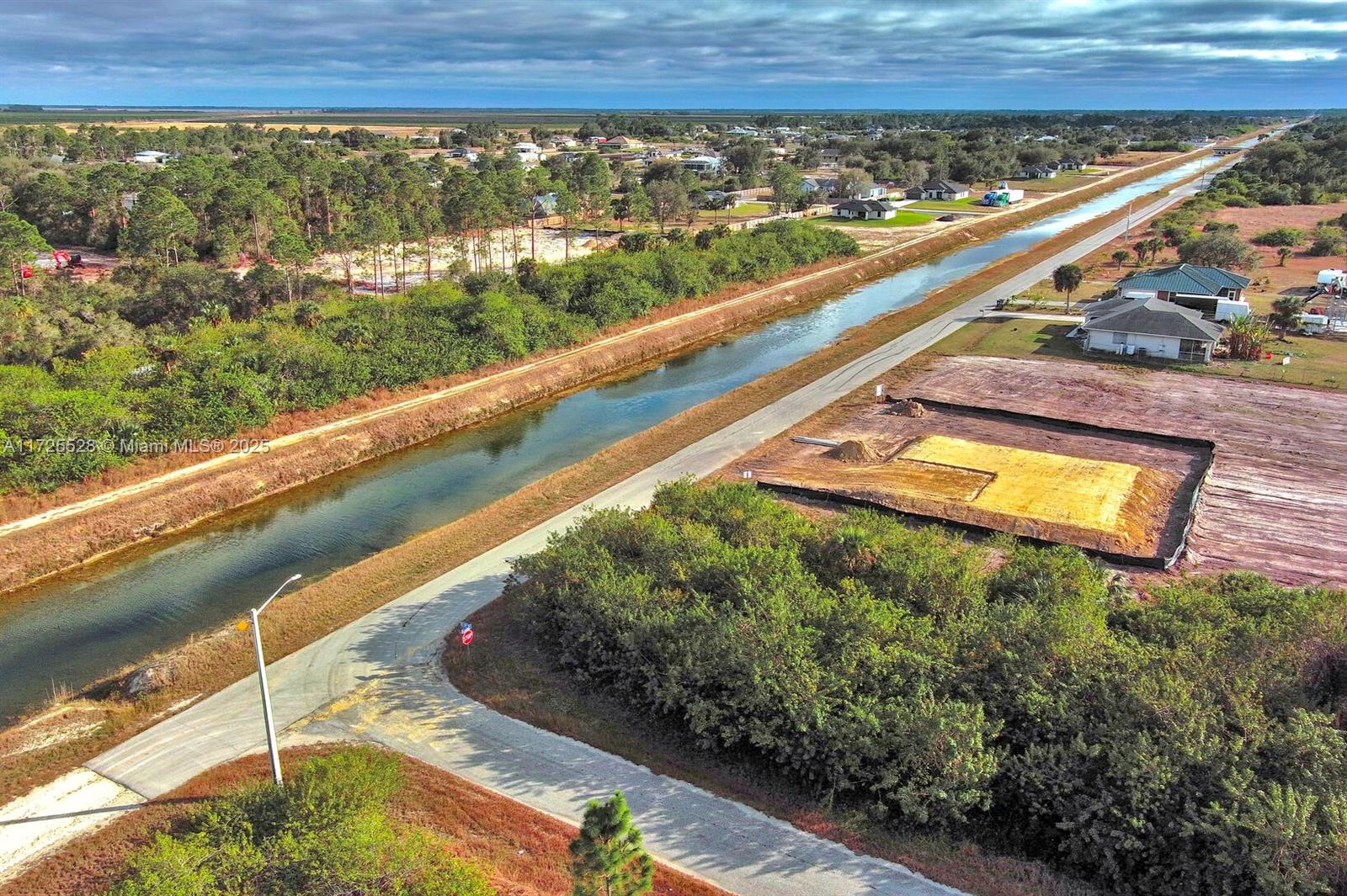An aerial view shows a canal, a paved road, and a cleared residential building lot — 4506 E 19th St, Lehigh Acres FL 33973, LEHIGH ACRES, FL