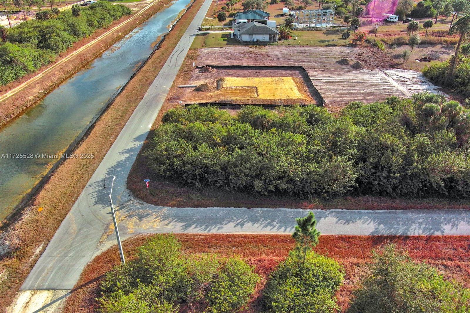 An aerial view shows a cleared residential lot with a foundation pad beside a canal — 4506 E 19th St, Lehigh Acres FL 33973, LEHIGH ACRES, FL