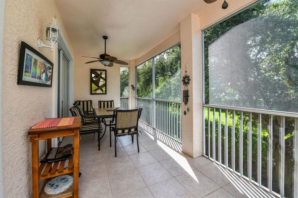 A screened-in patio features tile flooring, a ceiling fan, and outdoor dining furniture — 4228 CENTRAL SARASOTA PARKWAY UNIT 1024, SARASOTA, FL