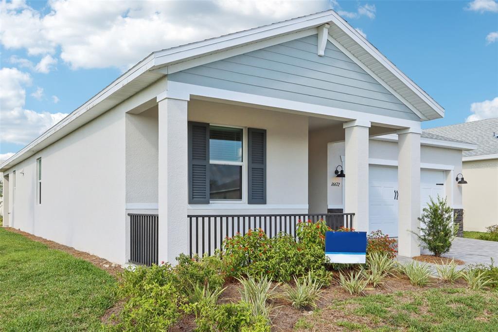 A single-story house with a light-colored stucco exterior, a front porch, and a blue sign — 16672 EXPEDITION COURT, PUNTA GORDA, FL
