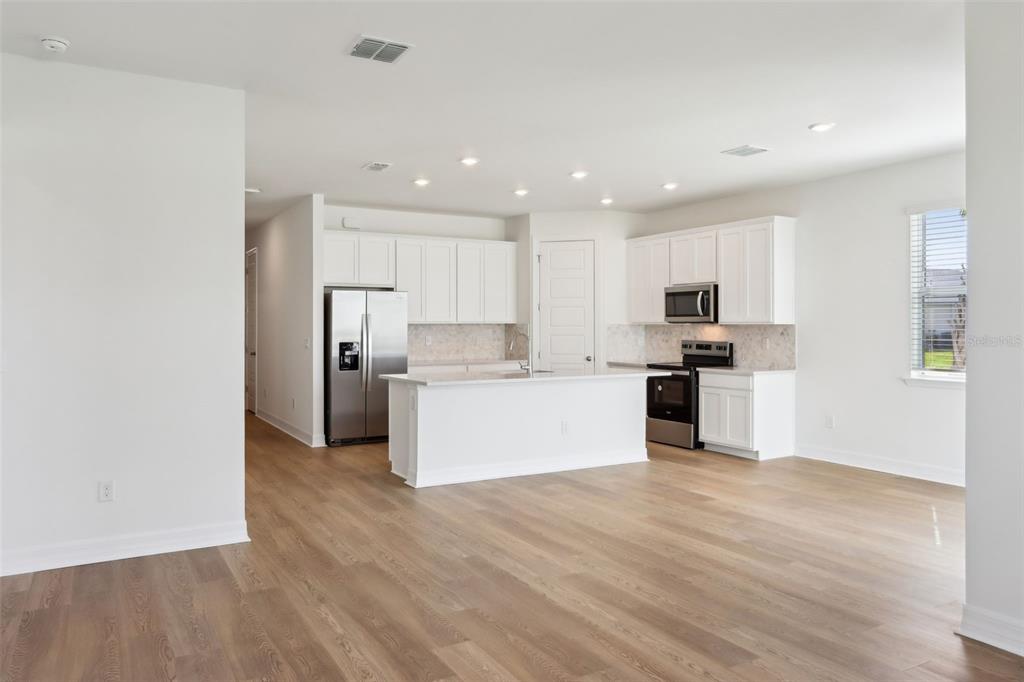 A kitchen with white cabinets, stainless steel appliances, and an island overlooks an open area — 16672 EXPEDITION COURT, PUNTA GORDA, FL