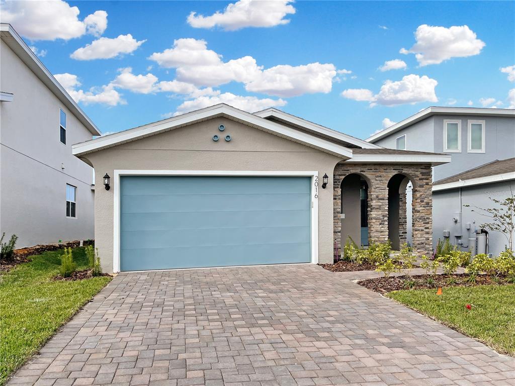 A single-story house features a blue garage door, stone-accented entryway, and a paved driveway — 2016 SUNSHINE PEAK DRIVE, MINNEOLA, FL