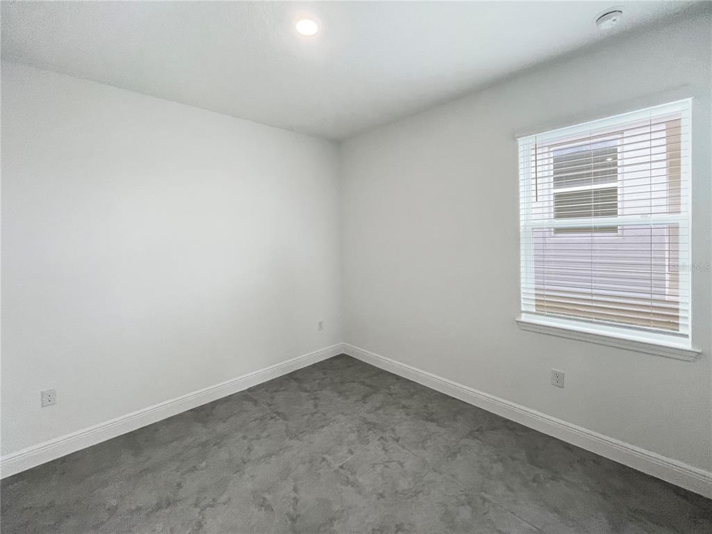 An empty room with white walls, gray tile flooring, and a window with blinds — 2016 SUNSHINE PEAK DRIVE, MINNEOLA, FL