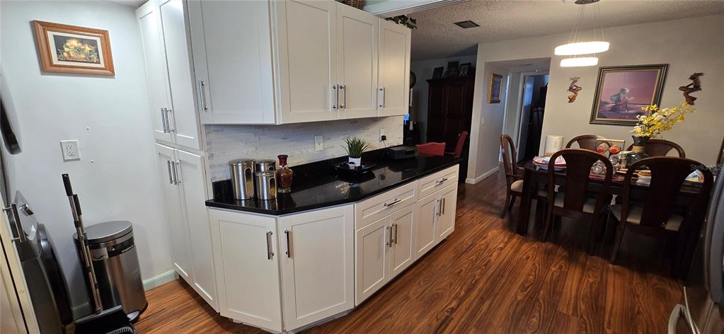 A kitchen with white cabinets, black countertops, and a dining area with wood flooring — 3894 37TH STREET S UNIT 41, ST PETERSBURG, FL