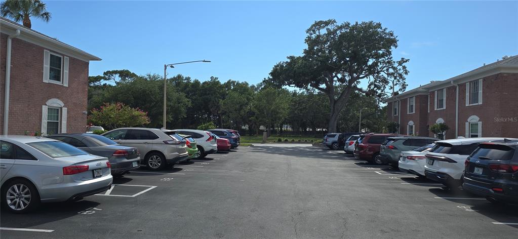 A parking lot sits between two brick apartment buildings under a clear blue sky — 3894 37TH STREET S UNIT 41, ST PETERSBURG, FL
