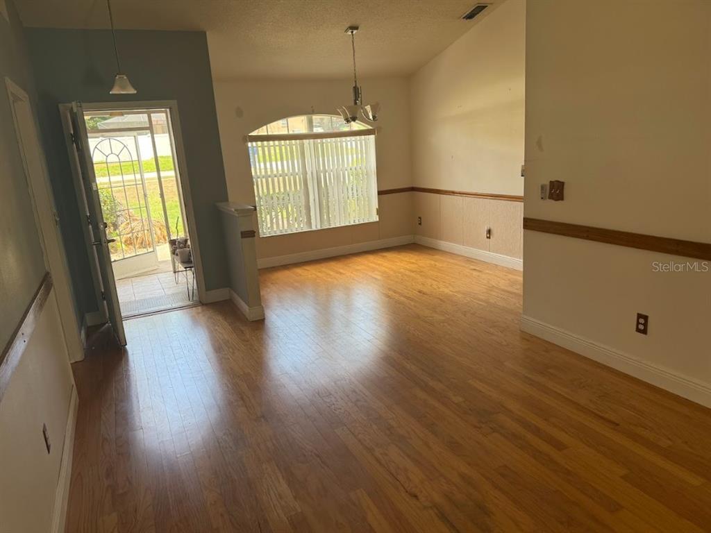 An empty dining room features hardwood floors, a chandelier, and a glass-paneled exterior door — 744 MEADOW PARK DRIVE, MINNEOLA, FL