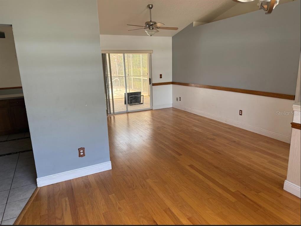 A living room with hardwood floors, a ceiling fan, and sliding glass doors to a patio — 744 MEADOW PARK DRIVE, MINNEOLA, FL