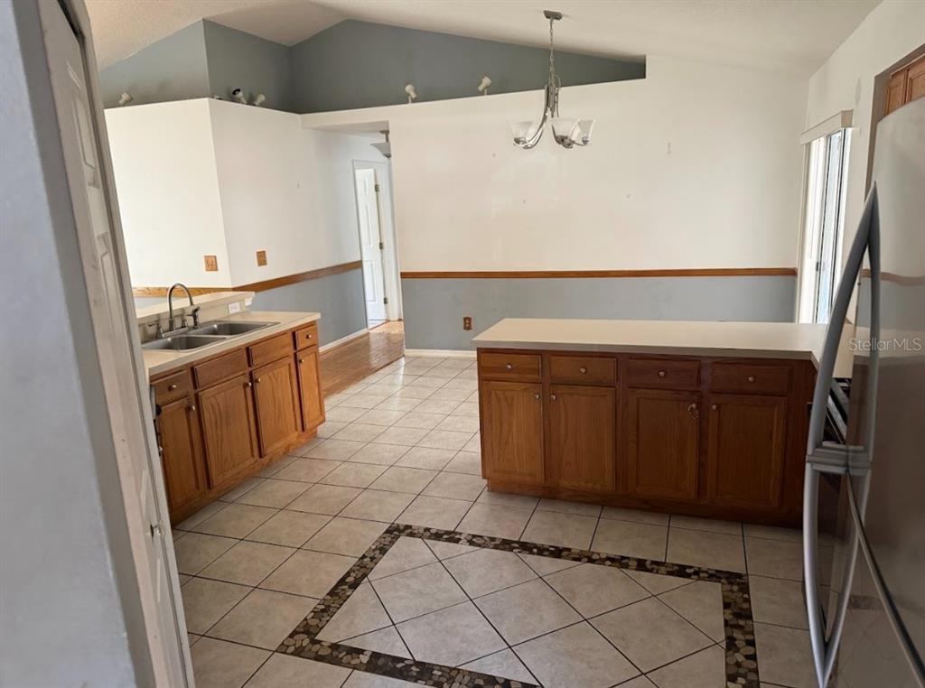 A kitchen features oak cabinets, a central island, tile flooring, and a vaulted ceiling — 744 MEADOW PARK DRIVE, MINNEOLA, FL