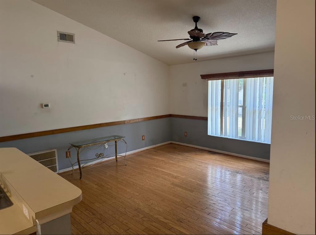 An empty room with hardwood floors, a ceiling fan, and a two-tone wall finish — 744 MEADOW PARK DRIVE, MINNEOLA, FL