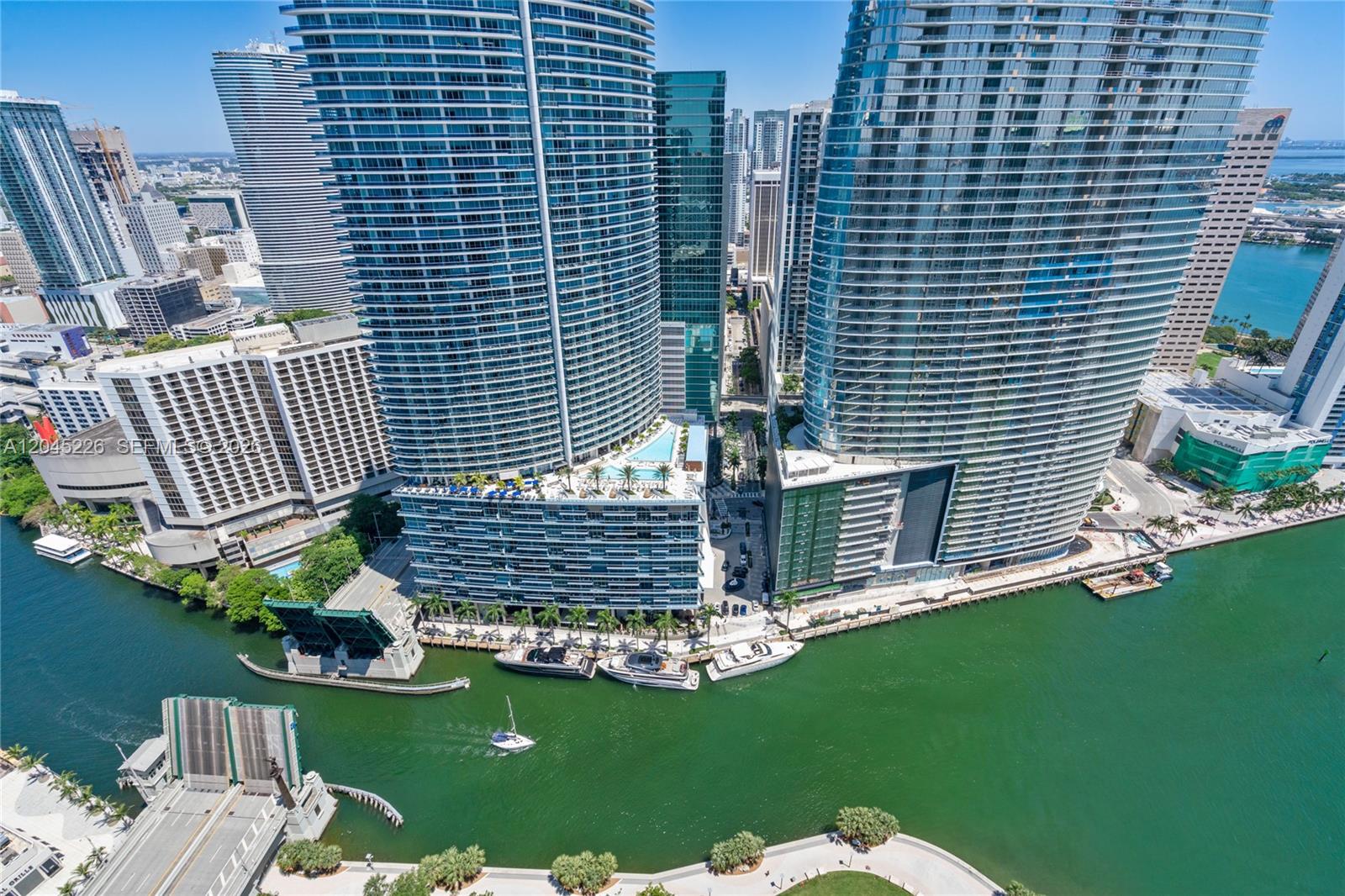 An aerial view of high-rise apartment buildings along a river with boats and a bridge — 475 Brickell Ave # 4315, Miami FL 33131, MIAMI, FL