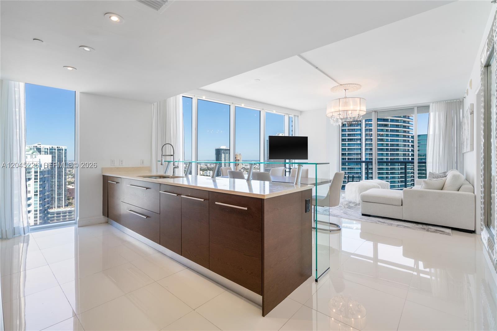 A modern kitchen with dark wood cabinets and a glass-topped island overlooks a city skyline — 475 Brickell Ave # 4315, Miami FL 33131, MIAMI, FL