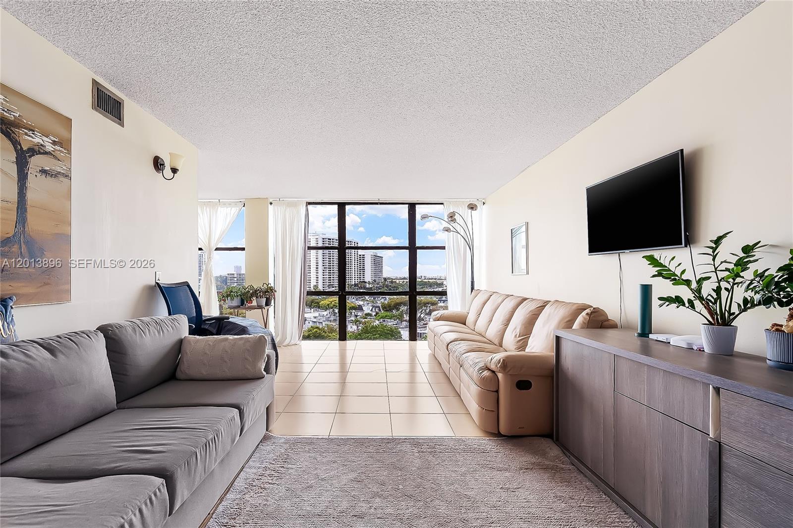 A living room features a gray sofa, a beige leather couch, and large floor-to-ceiling windows — 800 Parkview Dr # 901, Hallandale Beach FL 33009, HALLANDALE BEACH, FL