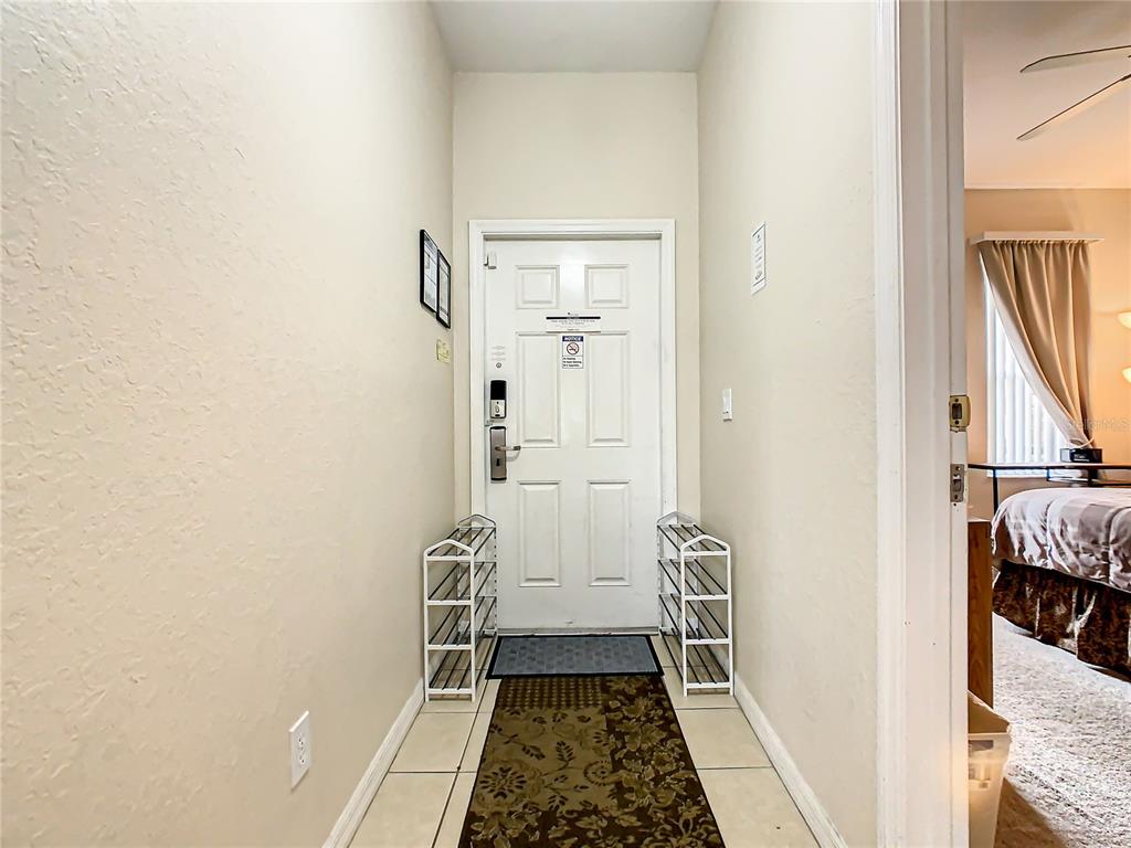 An entryway features a white front door, tiled floors, and two metal shoe racks — 702 CALABRIA AVE, DAVENPORT, FL