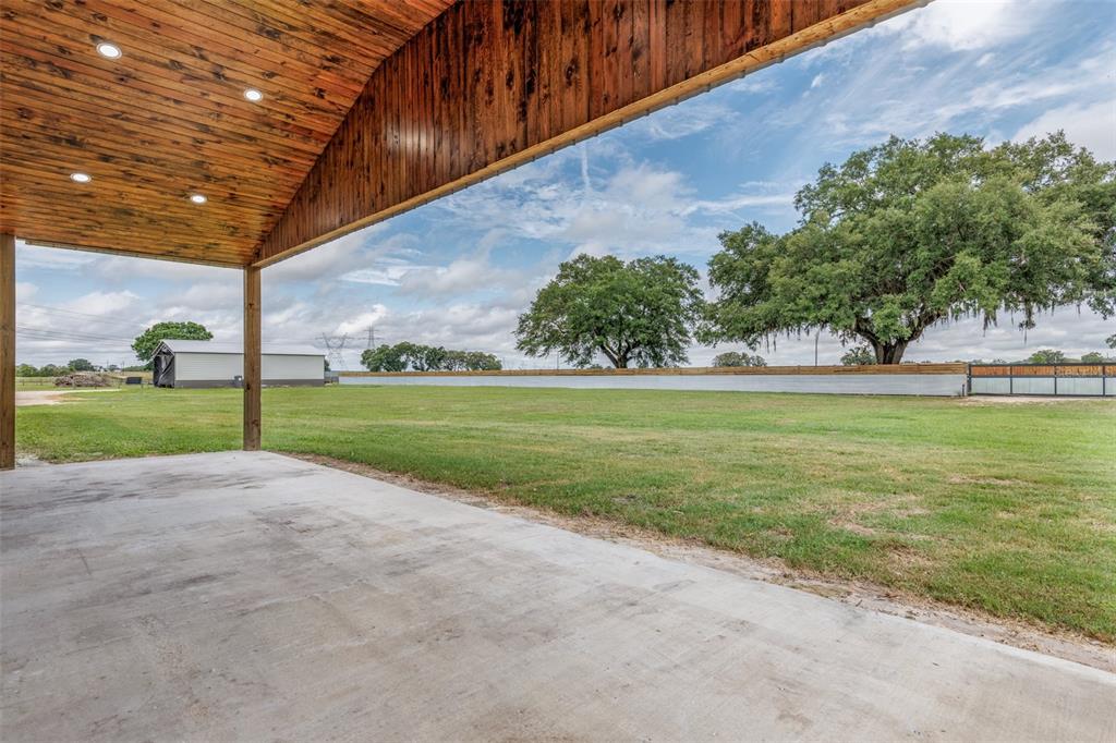 A covered concrete patio overlooks a large grassy yard with mature trees and a fence — 1285 NW 102ND A BOULEVARD, WILDWOOD, FL
