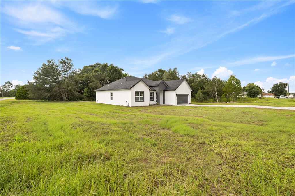A modern white house with a dark roof sits on a large, grassy lot — 14144 SW 47 AVENUE, OCALA, FL