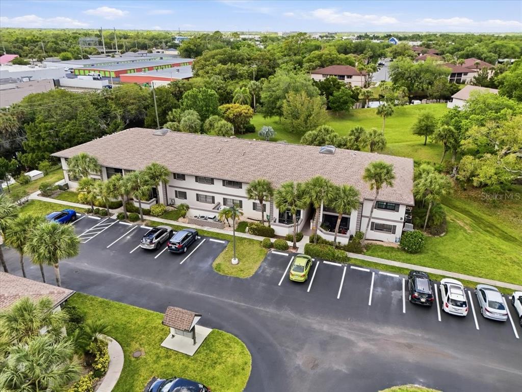 An aerial view shows a multi-story apartment building with a parking lot and surrounding greenery — 1515 FORREST NELSON BOULEVARD UNIT B206, PORT CHARLOTTE, FL