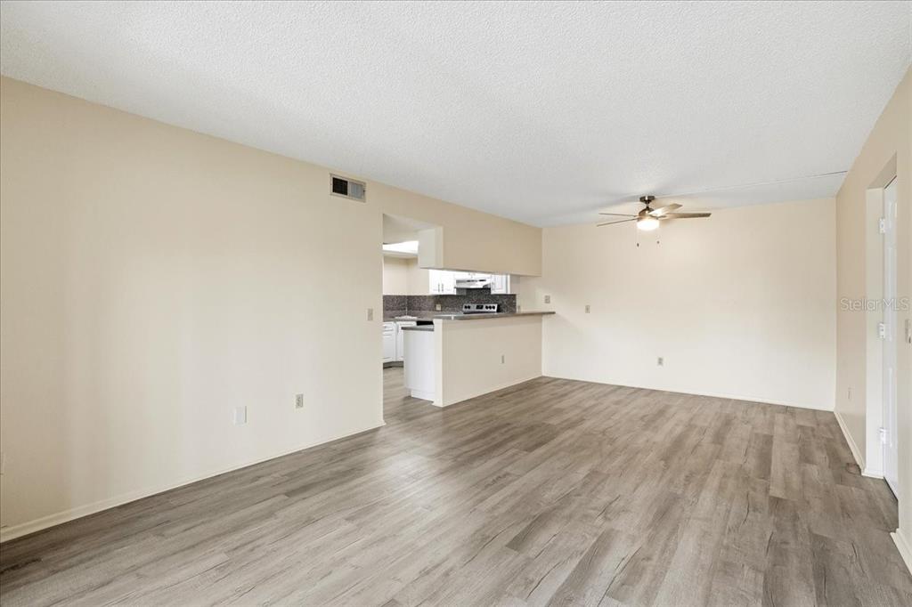 An open-concept living room features light-colored walls, wood-look flooring, and a pass-through to the kitchen — 1515 FORREST NELSON BOULEVARD UNIT B206, PORT CHARLOTTE, FL