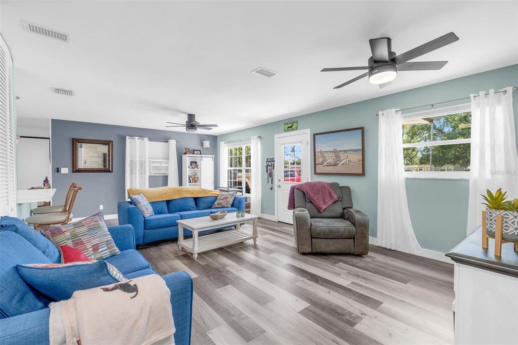 A living room features blue sofas, a gray recliner, wood-look flooring, and a ceiling fan — 2824 OAK LEA DRIVE, SOUTH DAYTONA, FL