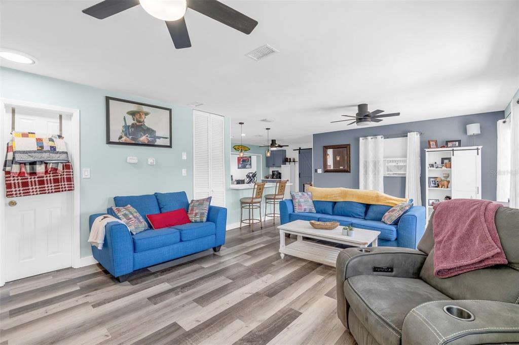 A living room features blue sofas, a gray recliner, and wood-look flooring under ceiling fans — 2824 OAK LEA DRIVE, SOUTH DAYTONA, FL