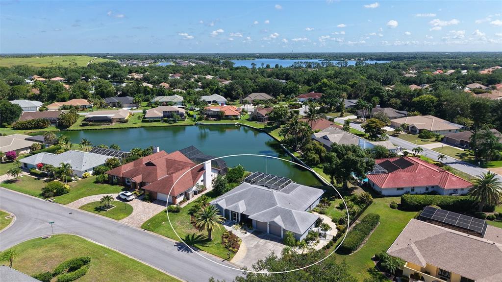 An aerial view shows a single-story house with a gray roof and pool enclosure — 6988 COUNTRY LAKES CIRCLE, SARASOTA, FL