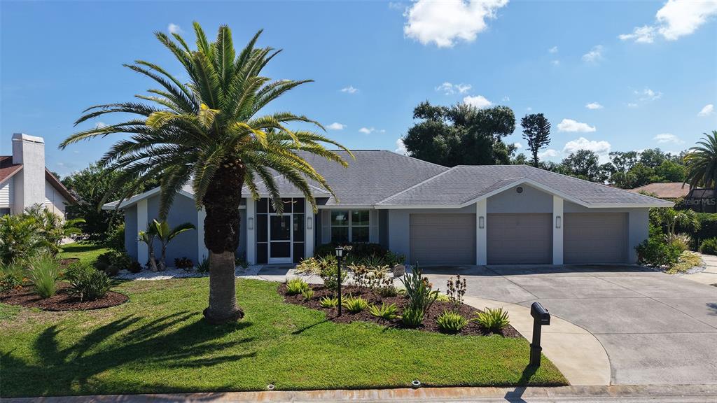 A single-story house with a three-car garage, a large palm tree, and a landscaped yard — 6988 COUNTRY LAKES CIRCLE, SARASOTA, FL